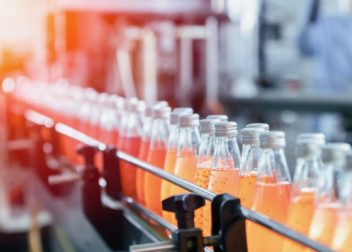 Bouteilles en verre fermée remplies d'un liquide orange qui sont dans une usine