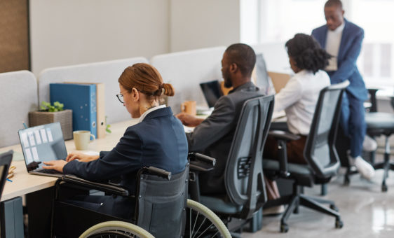 Woman In Wheelchair Working With Colleagues